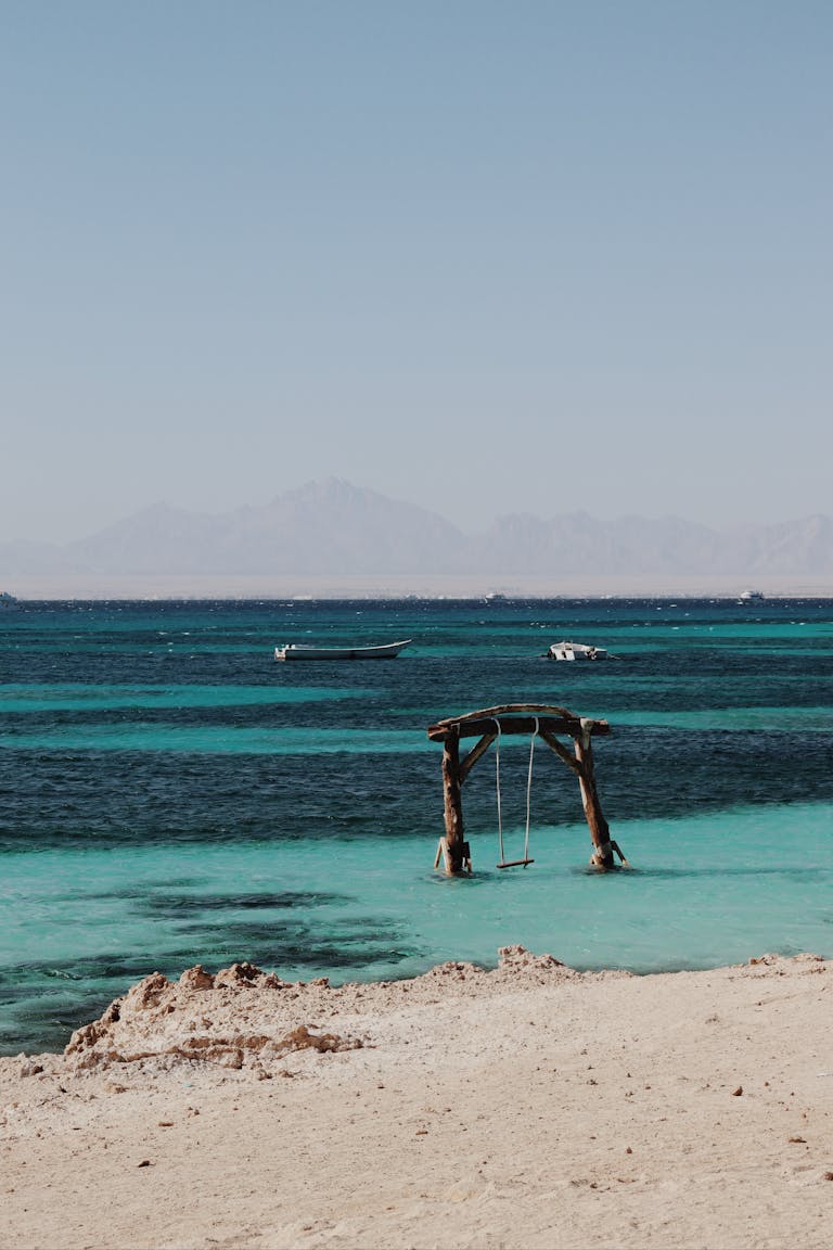 Peaceful beach scene with a swing over turquoise waters in Hurghada, Egypt.
