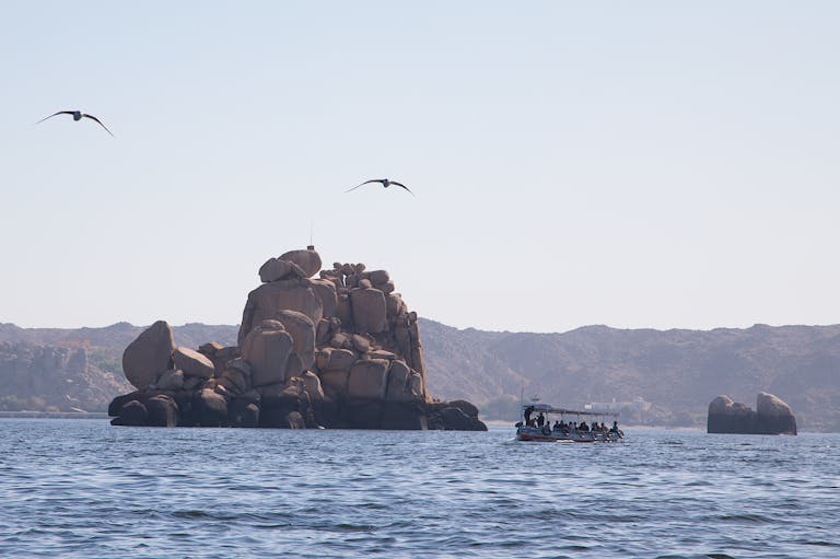 Turpis Tincidunt Idaliquet Risus Feugiat Molestie Tourists enjoy a tranquil boat ride on the Nile with a rocky island backdrop in Egypt.