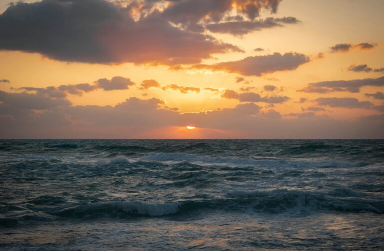 Captivating sunrise over Alexandria's rough sea, showcasing vivid clouds and waves.