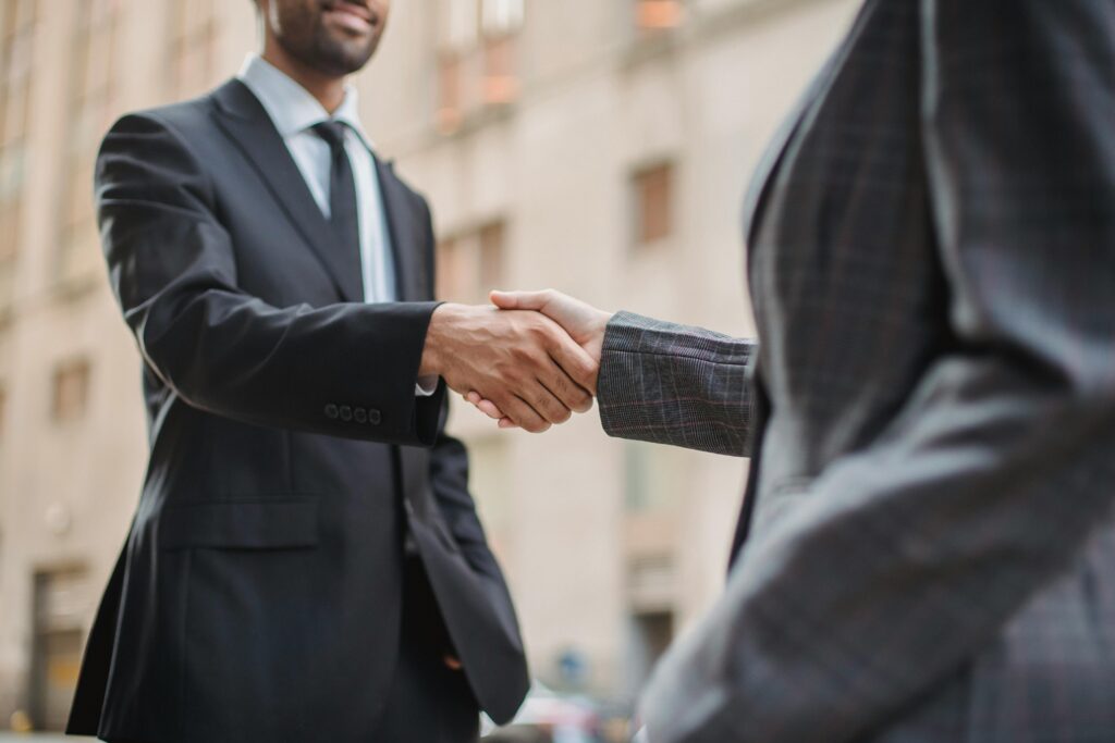 About Us Business professionals greeting each other with a handshake outdoors, symbolizing partnership.