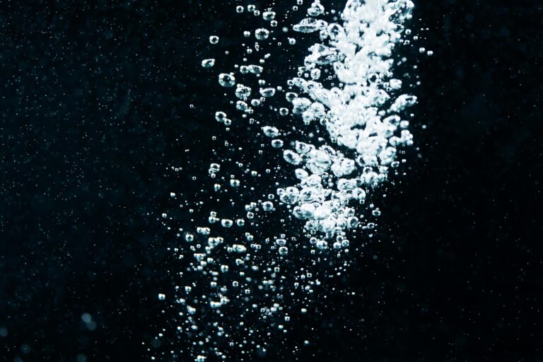 A close-up of effervescent water bubbles rising in a dark liquid, creating a vibrant and dynamic visual.