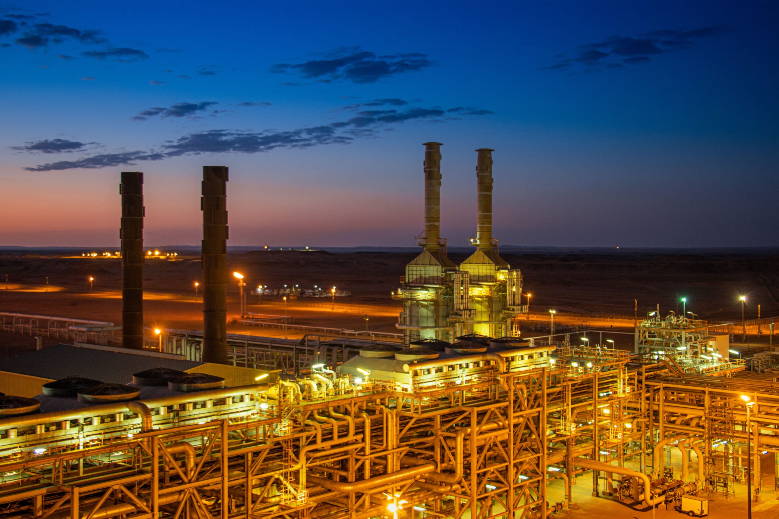 Environmental Site Assessment Reports for GC 15, GC 23 and GC 25 Aerial view of an illuminated factory with chimneys at sunset, showcasing industrial architecture.