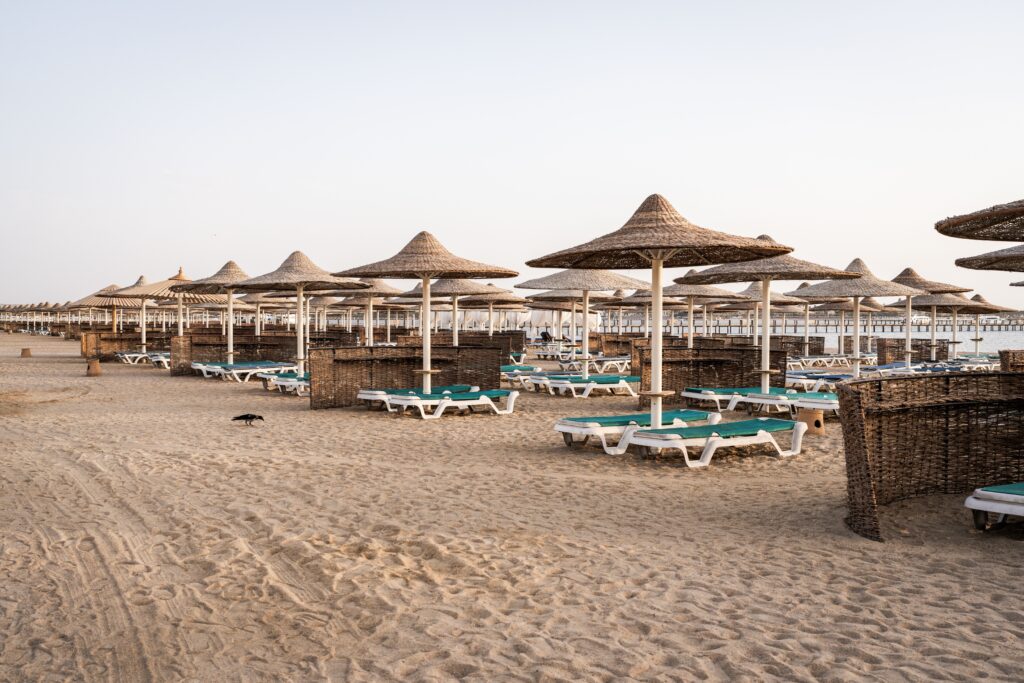 A serene view of straw sun umbrellas on the sandy beach of Hurghada, Egypt.