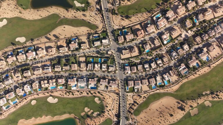 Aerial shot of luxury villas and golf course in Sheikh Zayed, Cairo, showcasing modern architecture and lush greenery.