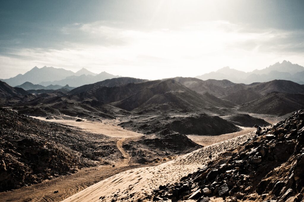 Breathtaking view of the Al Wahat Al Dakhla desert with rugged mountains under a bright sky.